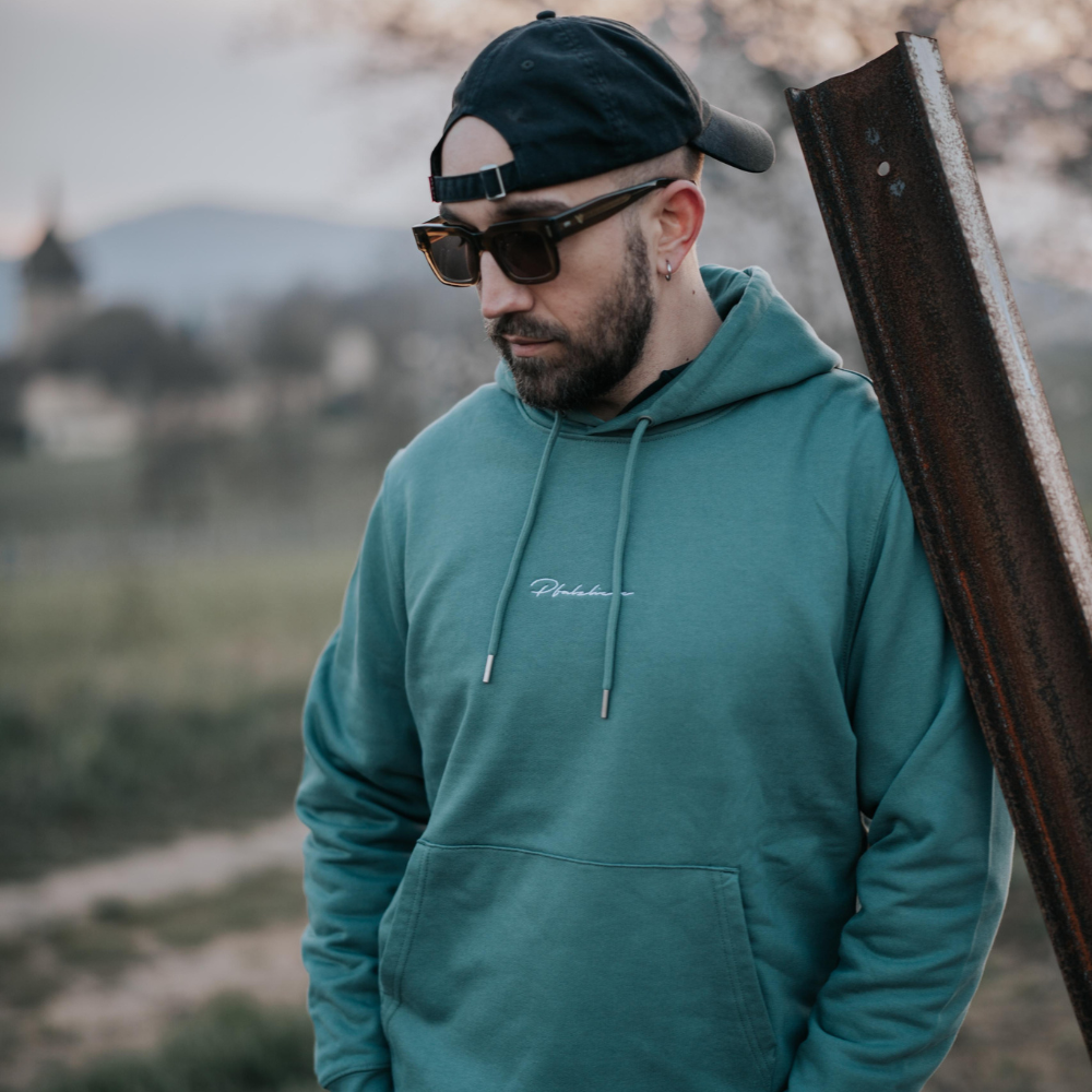 Ein Model steht angelehnt an einer Eisentange in den Weinbergen und trägt die VINO VISTA Sonnenbrille Silvaner.